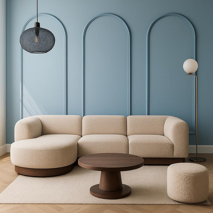 Minimalistische Japandi woonkamer met ronde beige bank, blauwe muur en sierlijsten in klassieke boogvorm
